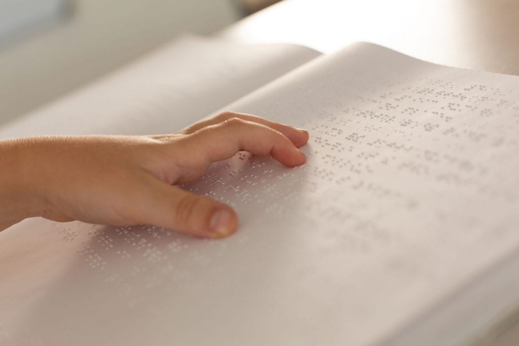 Mano de persona invidente sobre libro en braile
