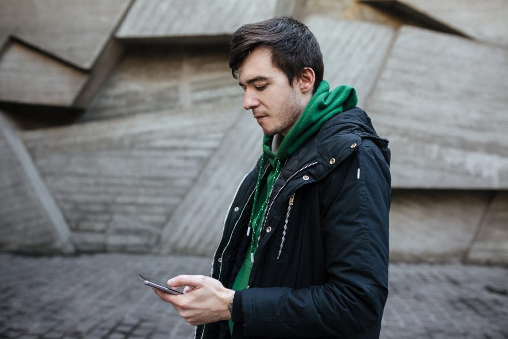 Hombre caminando por la calle con un teléfono en la mano