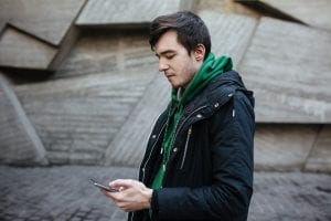 Hombre caminando por la calle con un teléfono en la mano